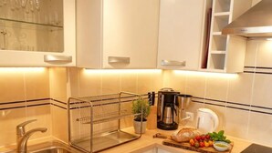 Een moderne keuken met een roestvrijstalen spoelbak, een koffiezetapparaat, een broodrooster en een snijplank met vers fruit en groenten.