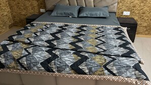 A bedroom with a bed, two nightstands, and a patterned bedspread. - Stay Royal Landran (Sahibzada Ajit Singh Nagar)