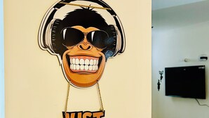 A wall with a large sticker of a smiling face wearing headphones and the text "JUST SMILE". - Stay Royal Landran (Sahibzada Ajit Singh Nagar)