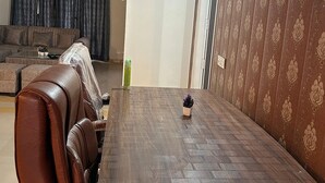 A dining table with a herringbone pattern, surrounded by brown leather chairs. - Stay Royal Landran (Sahibzada Ajit Singh Nagar)