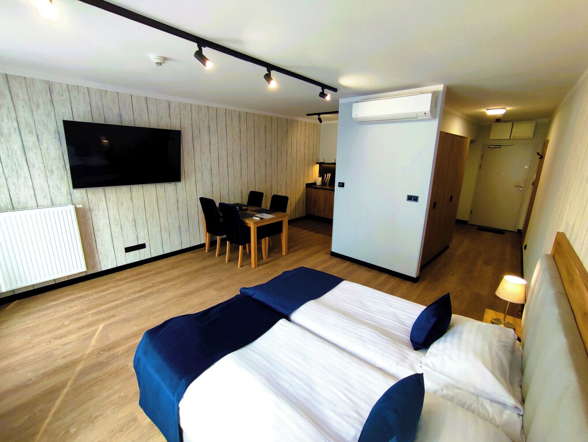 Een hotelkamer met een bed, een televisie, een bureau en een kitchenette.