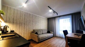 A modern living room with a sofa, a dining table, and a piano.
