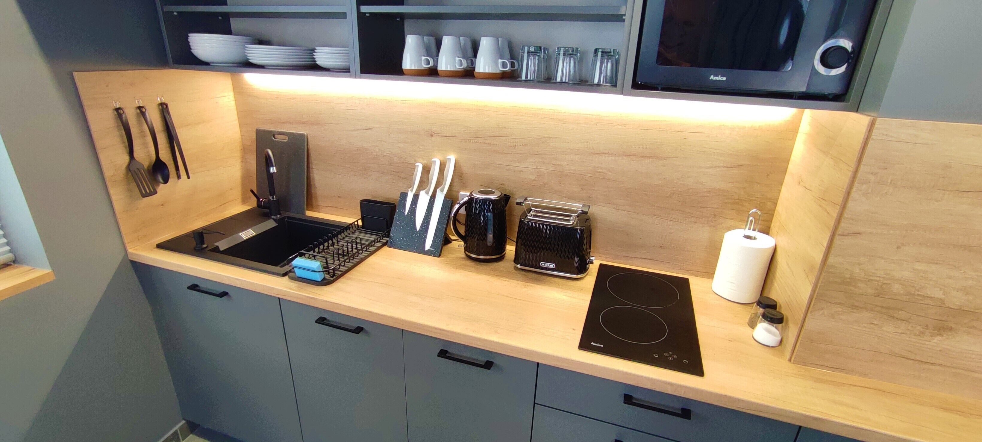 A modern kitchen with a wooden countertop, a built-in sink, and a black induction cooktop.