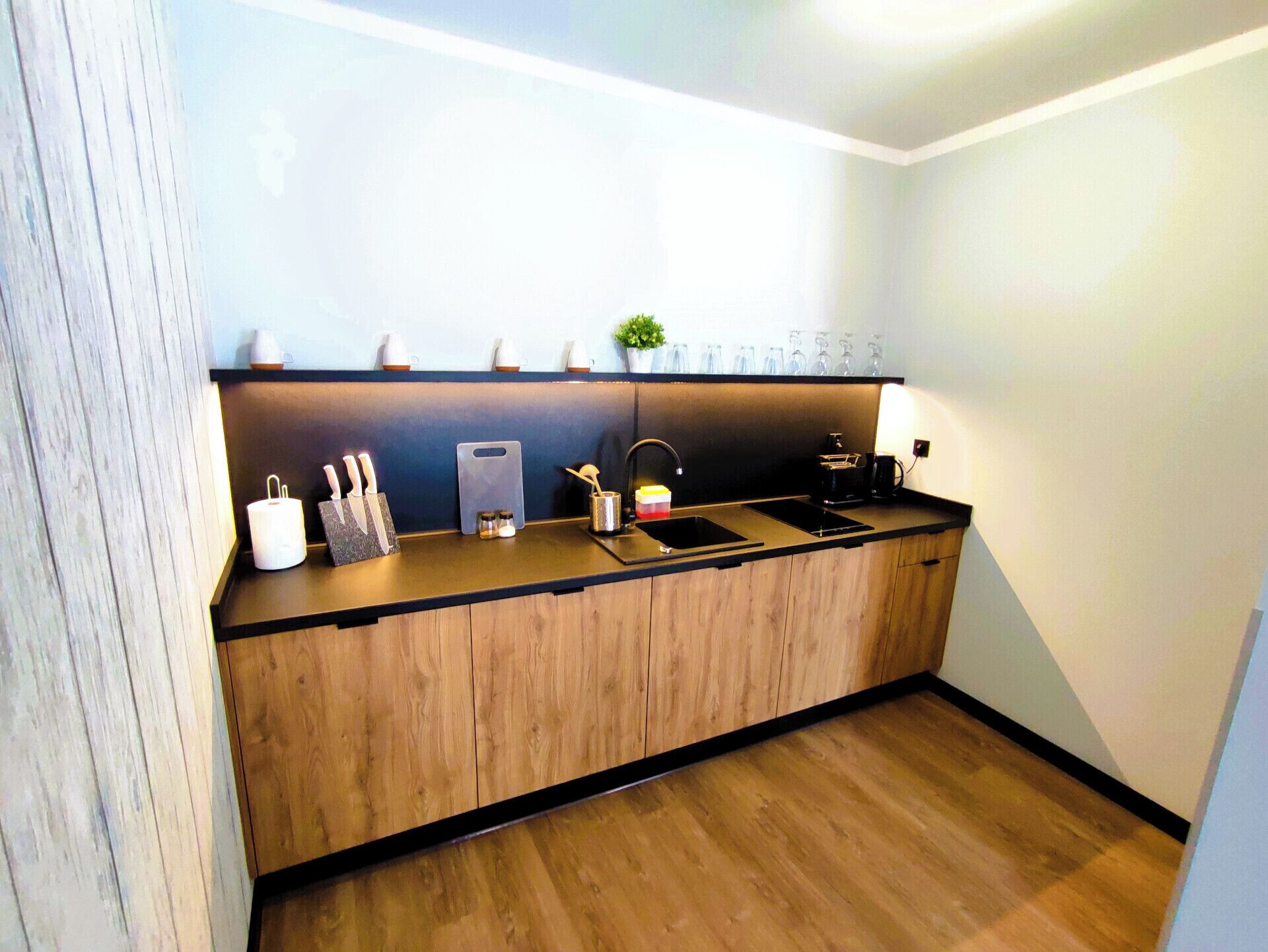A modern kitchen with a wooden countertop, a sink, and a coffee maker.