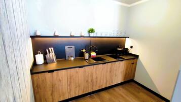 A modern kitchen with a wooden countertop, a sink, and a coffee maker.