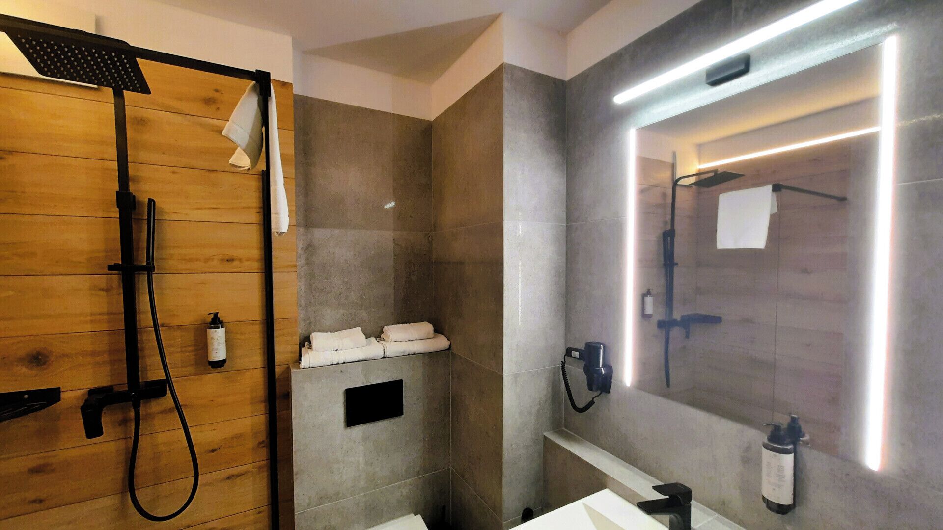 Une salle de bain moderne avec une cabine de douche en bois, un meuble-lavabo intégré avec un miroir et un porte-serviettes fixé au mur.