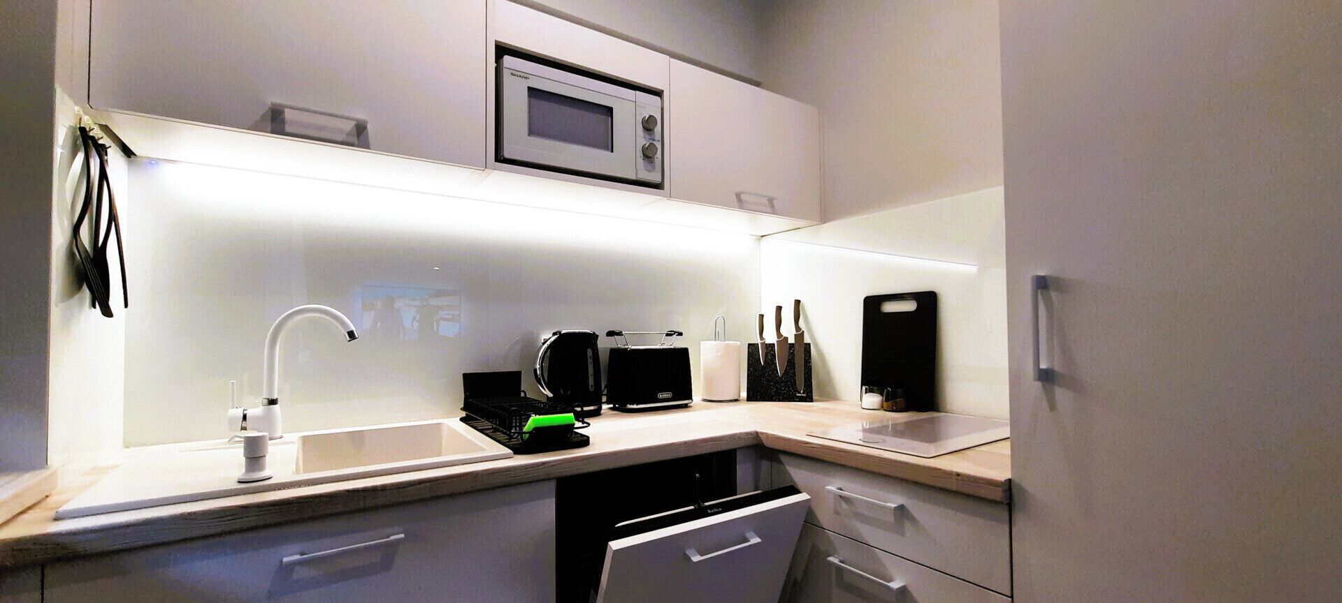Een moderne keuken met een magnetron, broodrooster en koffiezetapparaat op het aanrecht.