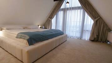 Un dormitorio con una cama grande, una mesita de noche y una ventana con cortinas.