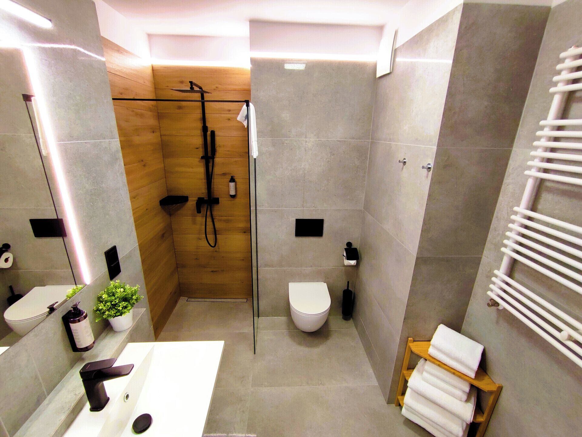 A modern bathroom with a shower, toilet, sink, and towel rack.