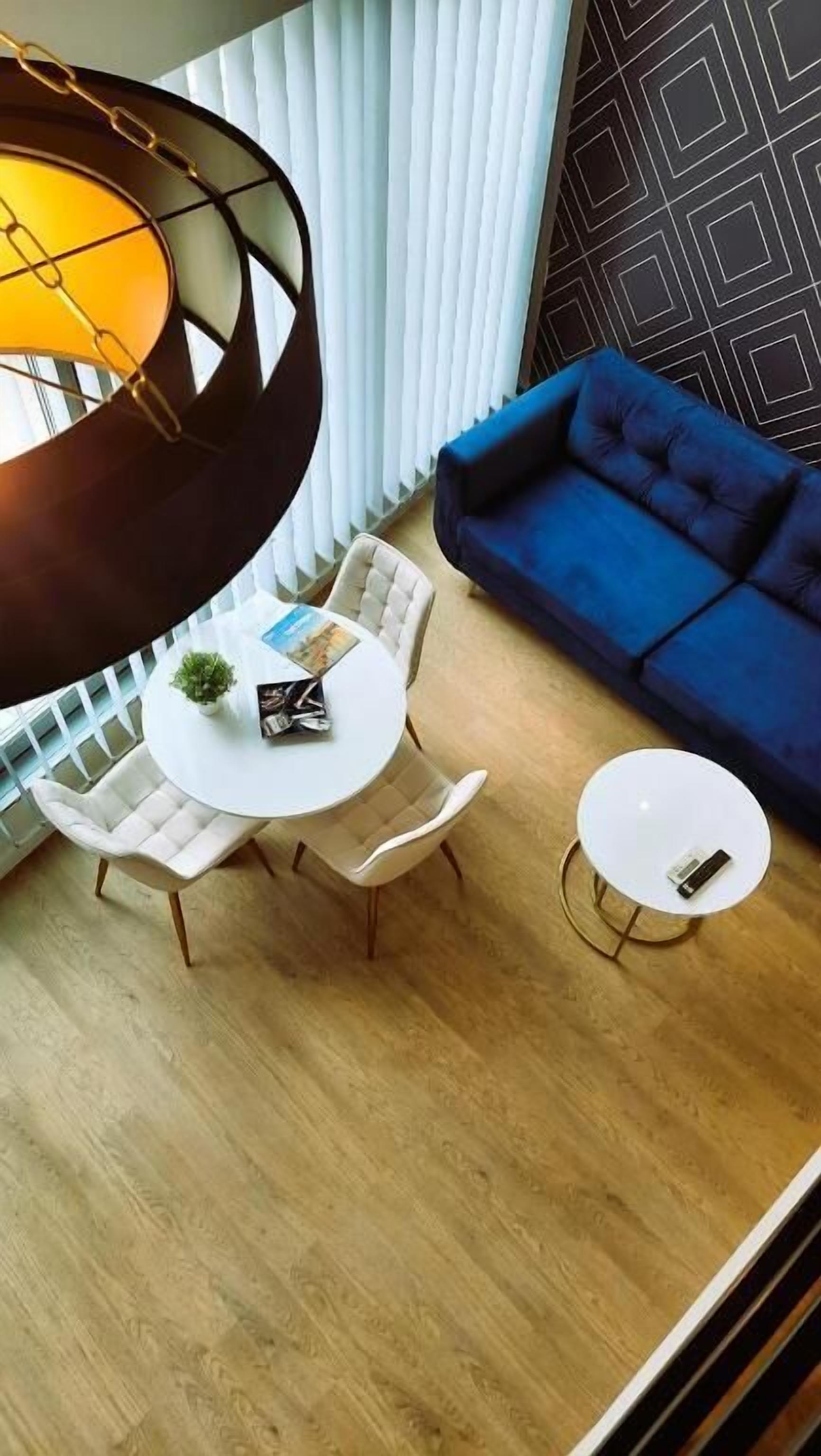 A modern living room with a blue sofa, a round white table, and a hanging light fixture.