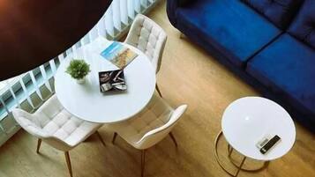 Una sala de estar moderna con un sofá azul, una mesa redonda blanca y una lámpara colgante.