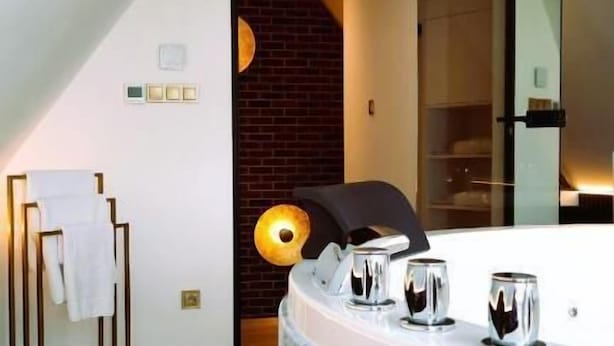 Un baño moderno con una bañera grande, un perchero y una pared de ladrillo.