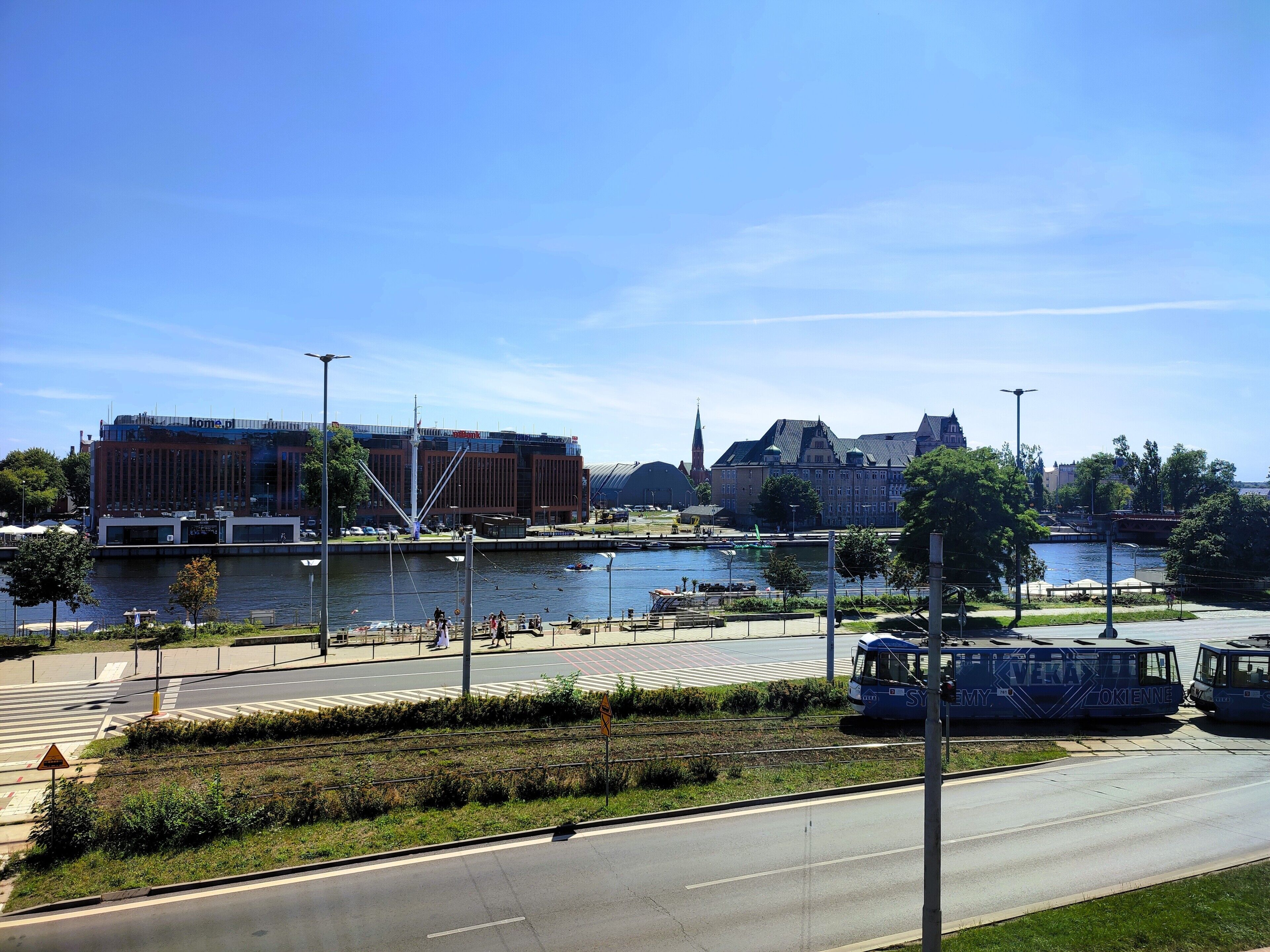 Une vue sur la rivière, avec un bâtiment moderne, une église et une ligne de tramway.