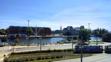 Une vue sur la rivière, avec un bâtiment moderne, une église et une ligne de tramway.