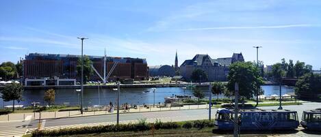 A riverside view with a modern building, a church, and a tram line.