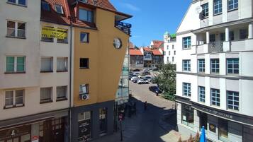 A street view with buildings, including a yellow building with a sign, a white building with a sign, and a blue awning.