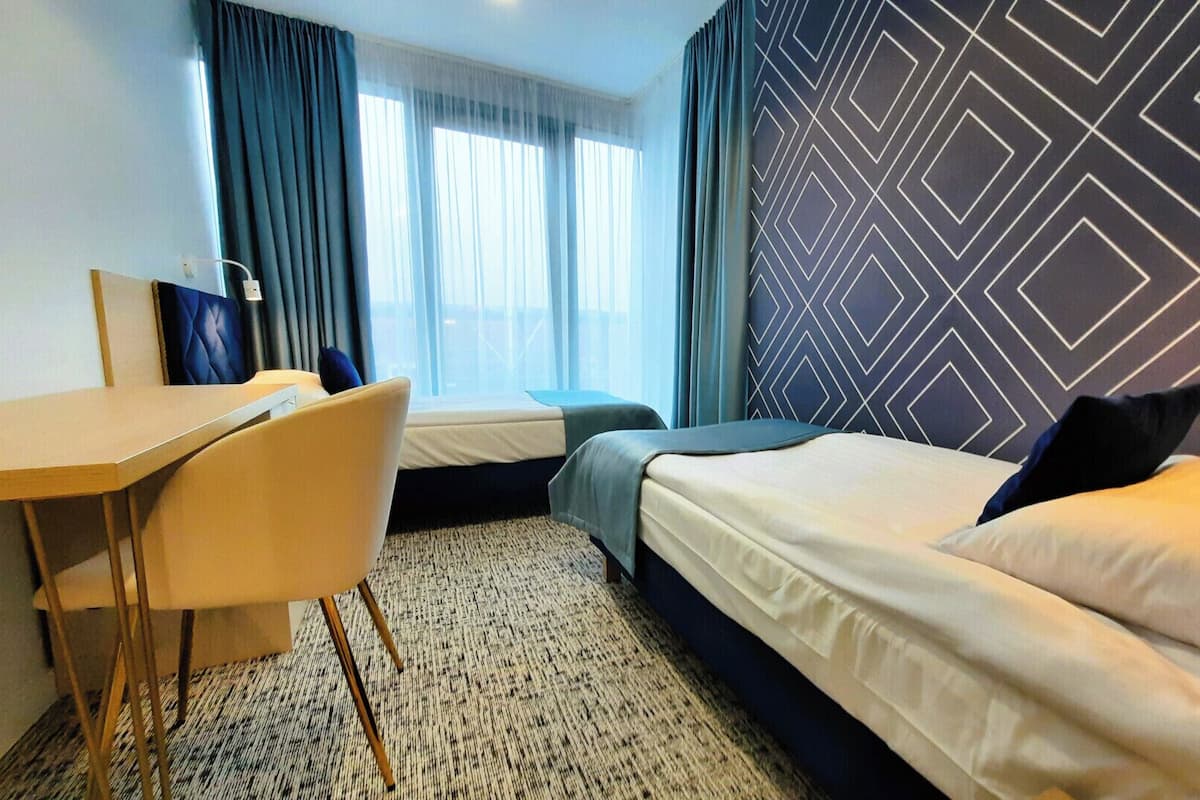A hotel room with a bed, a desk, and a chair.