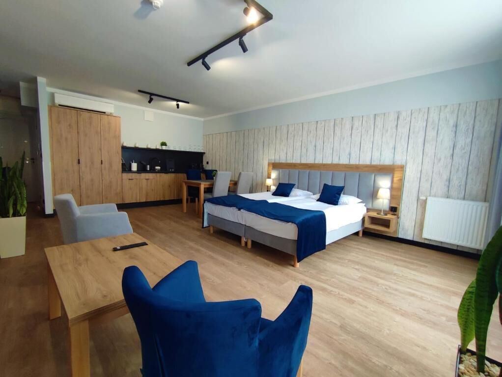 Een moderne hotelkamer met een houten vloer, een bed met hoofdeinde, een bureau en een stoel.