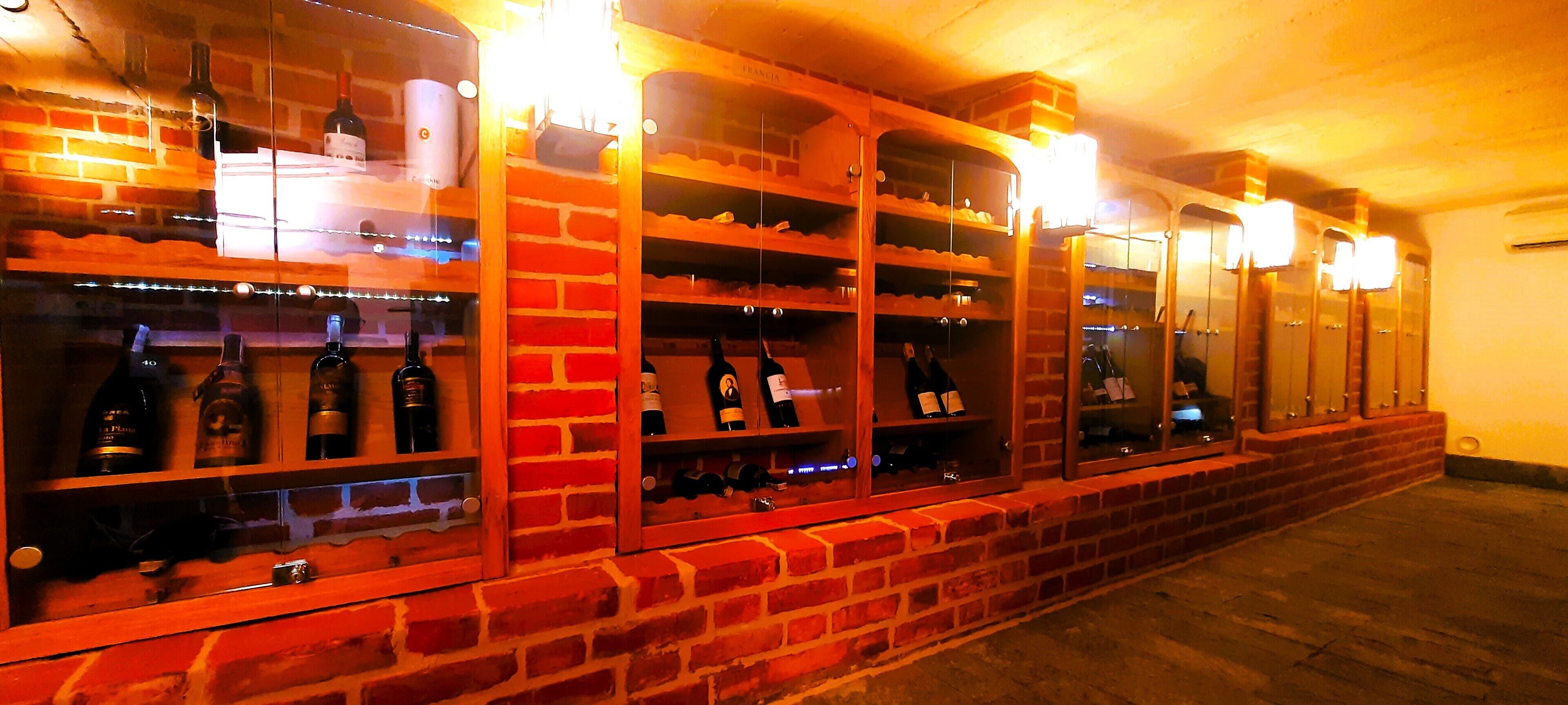 A wine cellar with brick walls and shelves holding bottles.