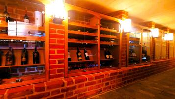 A wine cellar with brick walls and shelves holding bottles.