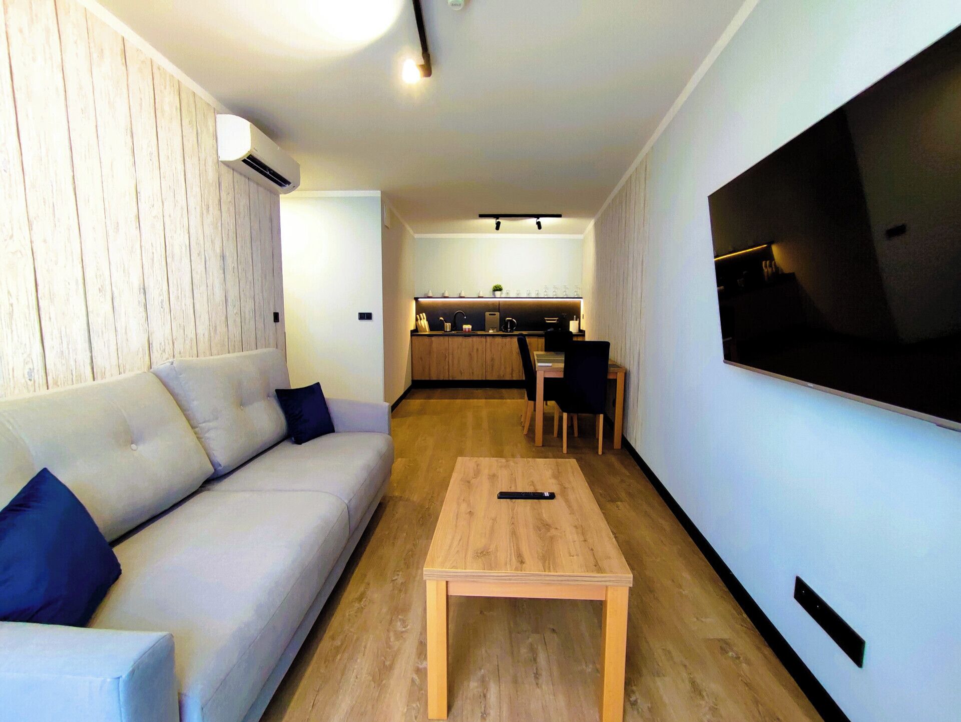 Una sala de estar moderna con un sofá, una mesa de centro y un televisor montado en la pared.