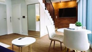 Un interior moderno con una escalera, una mesa redonda con sillas y un sofá azul.