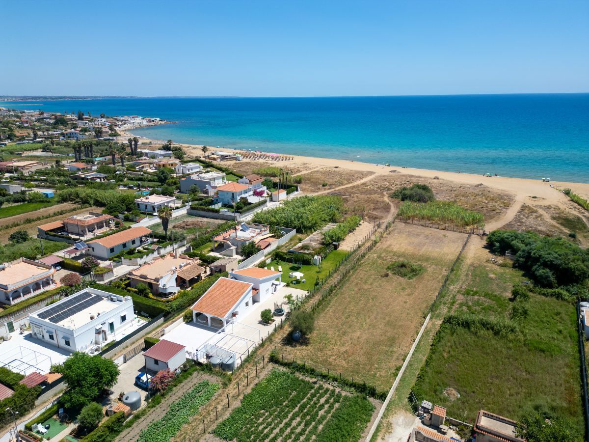 A coastal residential area with houses, a beach, and a clear view of the sea.