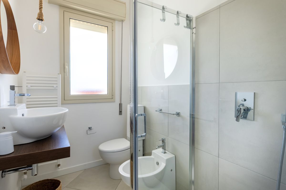 Ein modernes Badezimmer mit einer Duschkabine, einem weißen Waschbecken und einer Toilette.