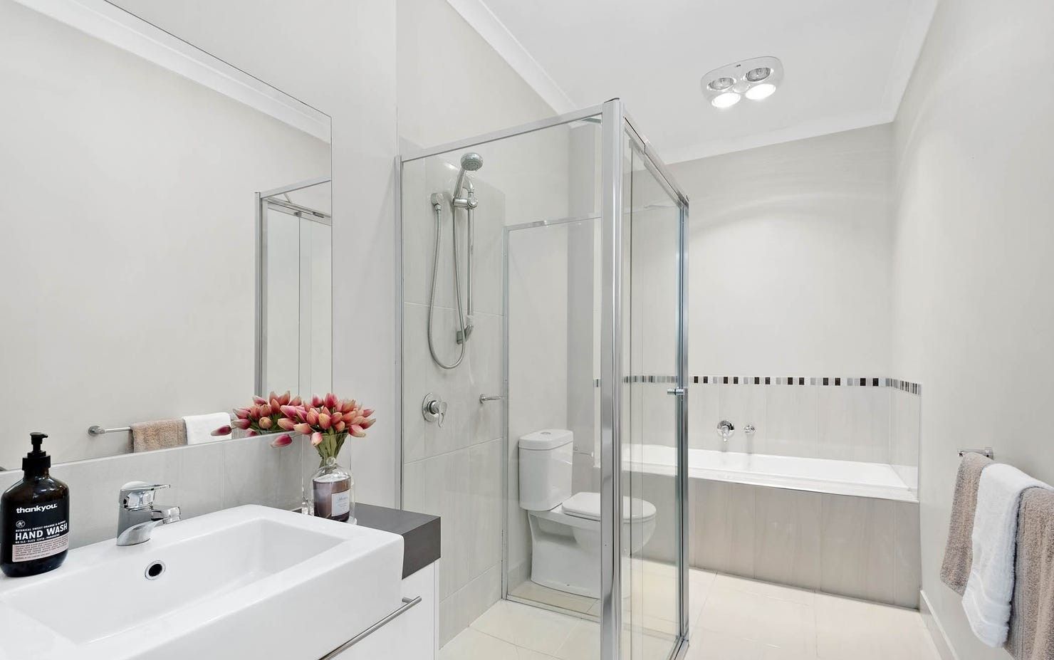 A modern bathroom with a glass-enclosed shower, a white sink, and a toilet.
