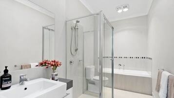 A modern bathroom with a glass-enclosed shower, a white sink, and a toilet.