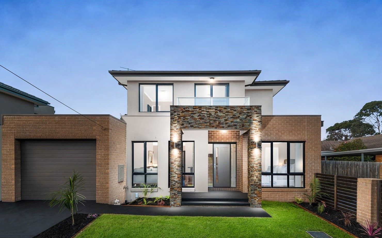 A modern two-story house with a garage, a stone archway entrance, and a well-maintained lawn.