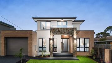 A modern two-story house with a garage, a stone archway entrance, and a well-maintained lawn.