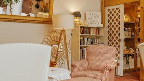 Une pièce chaleureuse avec un fauteuil à motifs à carreaux, une bibliothèque et un miroir décoratif.