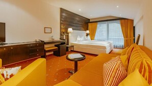 Une chambre d’hôtel équipée d’un lit, d’un canapé, d’un bureau, d’une télévision et d’une fenêtre avec des rideaux.
