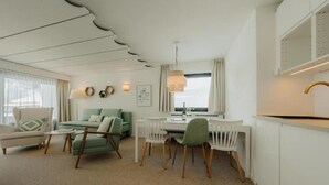 Un salon moderne comprenant un canapé, des fauteuils, une table à manger et un coin cuisine.