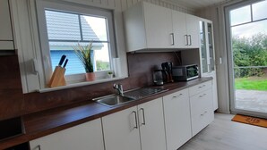 A modern kitchen with white cabinets, a stainless steel sink, and a microwave.