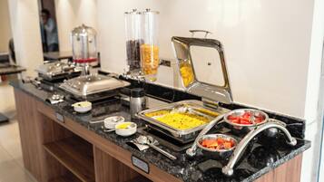 Una mesa de buffet con distintos alimentos y utensilios para servir.