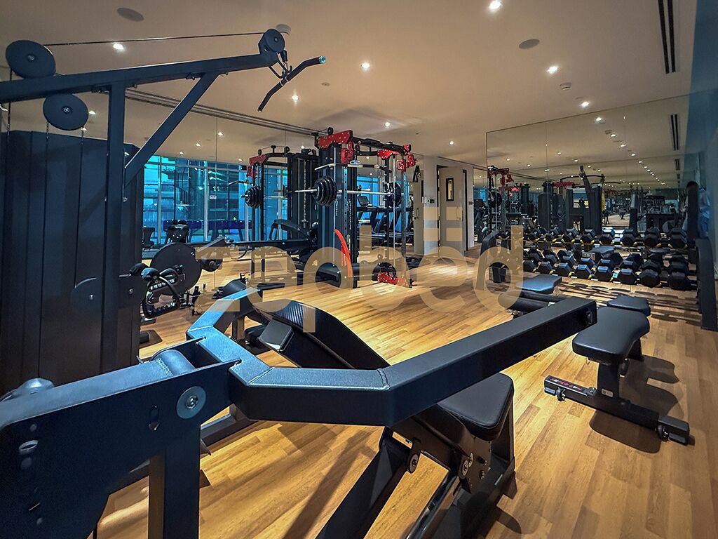 Ein Fitnessraum mit unterschiedlichen Trainingsgeräten, Holzböden und Spiegeln an den Wänden.