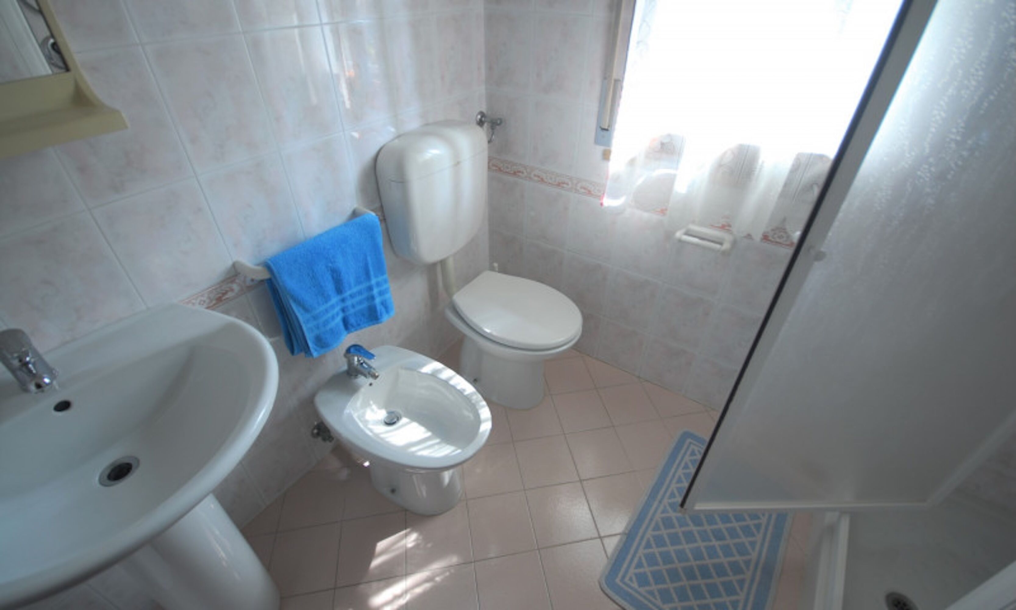 A bathroom with a sink, toilet, and bidet.
