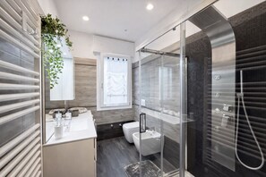 Ein modernes Badezimmer mit einer Duschkabine, einem weißen Waschbecken und einer Toilette.