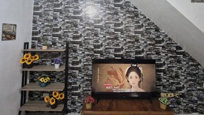 Ein Wohnzimmer mit einer Wand im Steinoptik, einem Holztv-Schrank und einer Treppe.