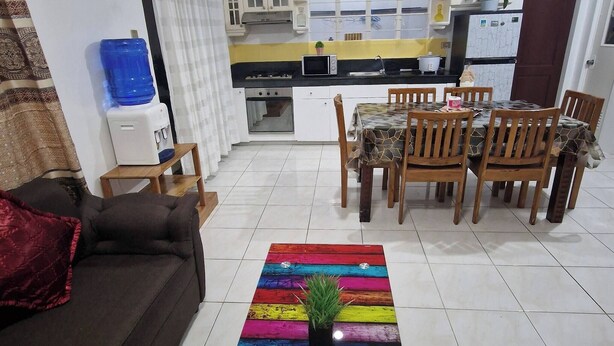 Ein Wohnzimmer mit einer Couch, einem Couchtisch mit Pflanze und einem Essbereich mit Tisch und Stühlen.