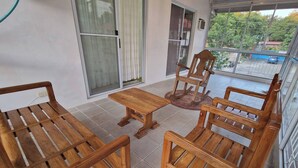 Ein Balkon mit Holzmöbeln, darunter ein Tisch und Stühle, und Blick ins Freie.