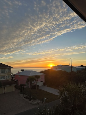 Une vue sur le coucher de soleil depuis un quartier résidentiel, avec des maisons et un ciel dégagé.