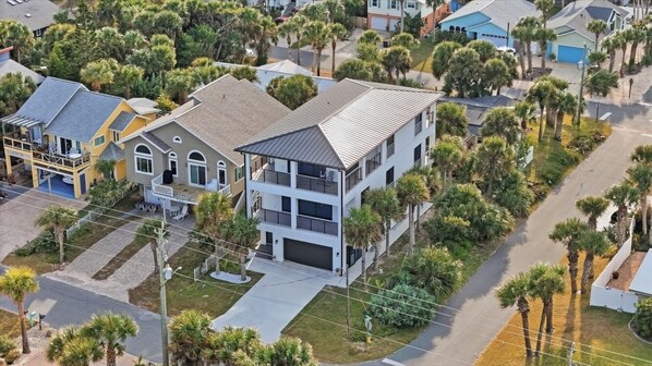 A multi-story residential building with a garage, surrounded by palm trees and a well-maintained lawn.