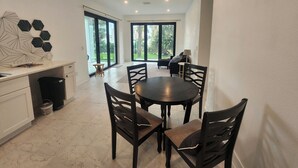 A modern kitchen with a dining area, large windows, and a view of greenery. - Lighthouse (Flagler Beach)