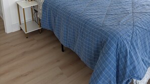 A bedroom with a bed, a bedside table, a lamp, and a floor lamp.
