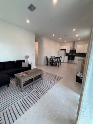 A modern living room with a sofa, coffee table, and dining area.