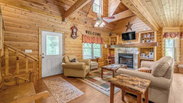 A cozy log cabin interior with a fireplace, a television, and a 'WELCOME' sign. - At Birch Hollow, we aim to provide a harmonious blend of tranquility, adventure, and comfort (Stanton)