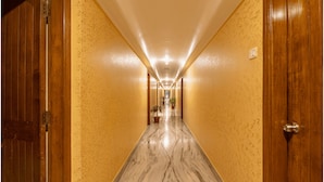 A long, narrow hallway with wooden doors on both sides, leading to a bright room at the end. - Mayur Hotel (Guwahati)